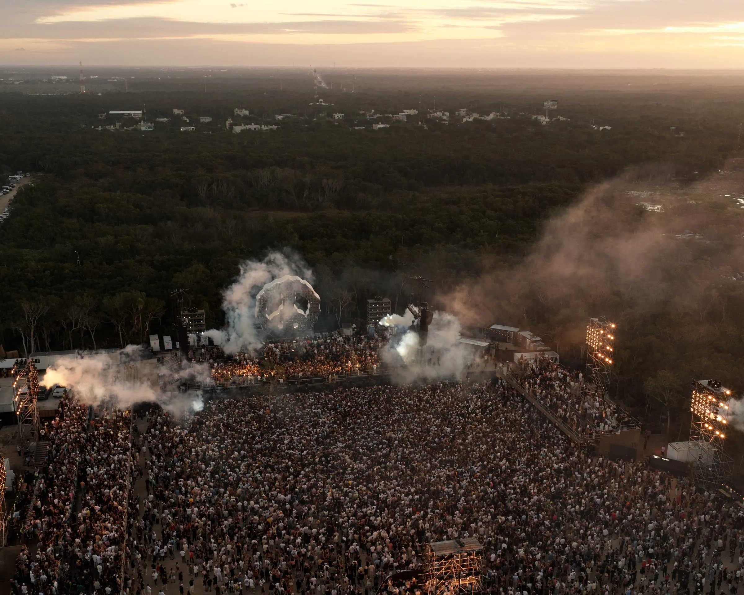 Aerial view of a large-scale live event in the Tulum jungle at sunset